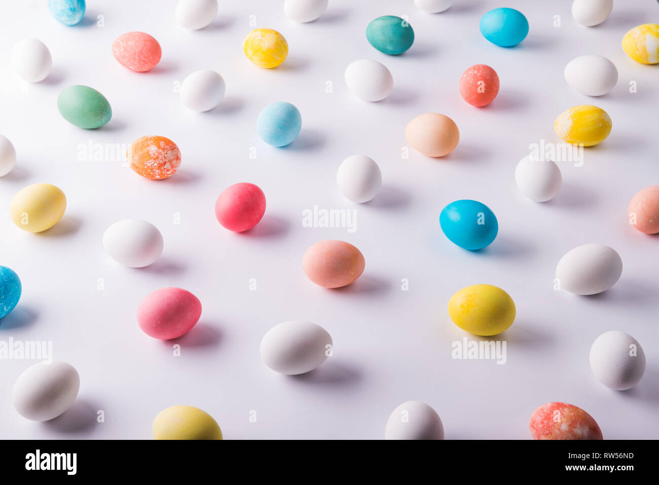 Colored eggs flat lay on a white background. Easter and spring ...