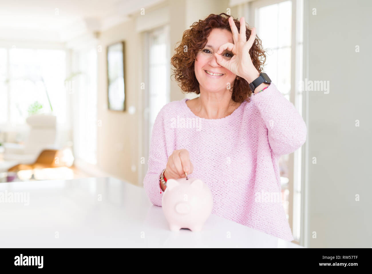 Senior woman saving money putting a coin inside piggy bank with happy ...