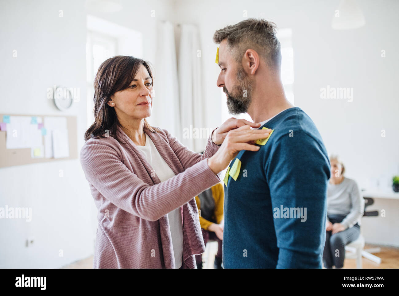Counsellor putting an adhesive notes on client during group therapy. Stock Photo