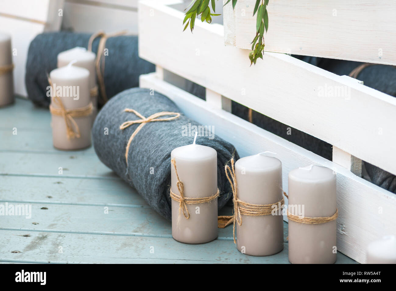 beautiful folded blankets and decorative white candles against white painted wooden crates. it all stands on the blue wooden floor Stock Photo