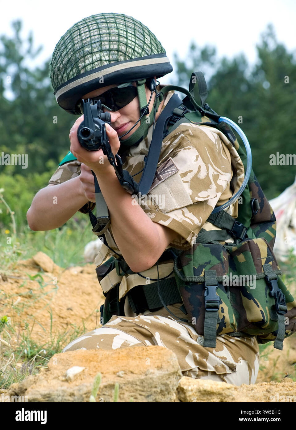 Female British soldier in desert uniform aiming her rifle. Stock Photo