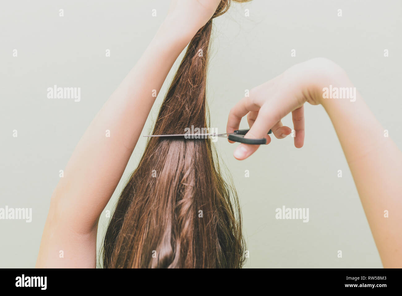 A young girl decided to cut her hair. In the hands of holding a bunch of  hair and scissors Stock Photo - Alamy