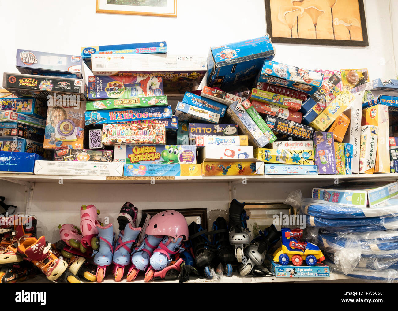 Board games, boxes of toys and roller blades in charity shop in Spain Stock Photo