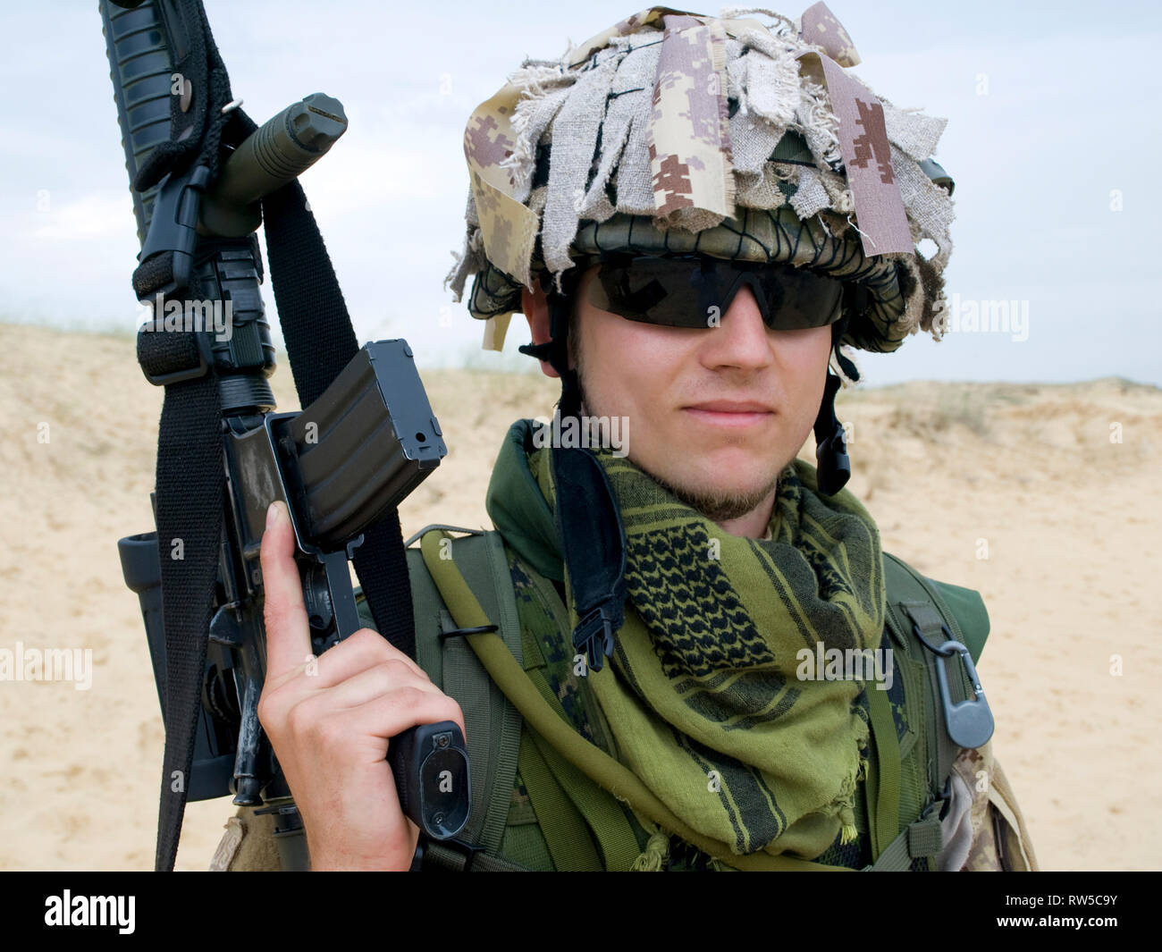 Soldier in desert uniform holding his rifle Stock Photo Alamy