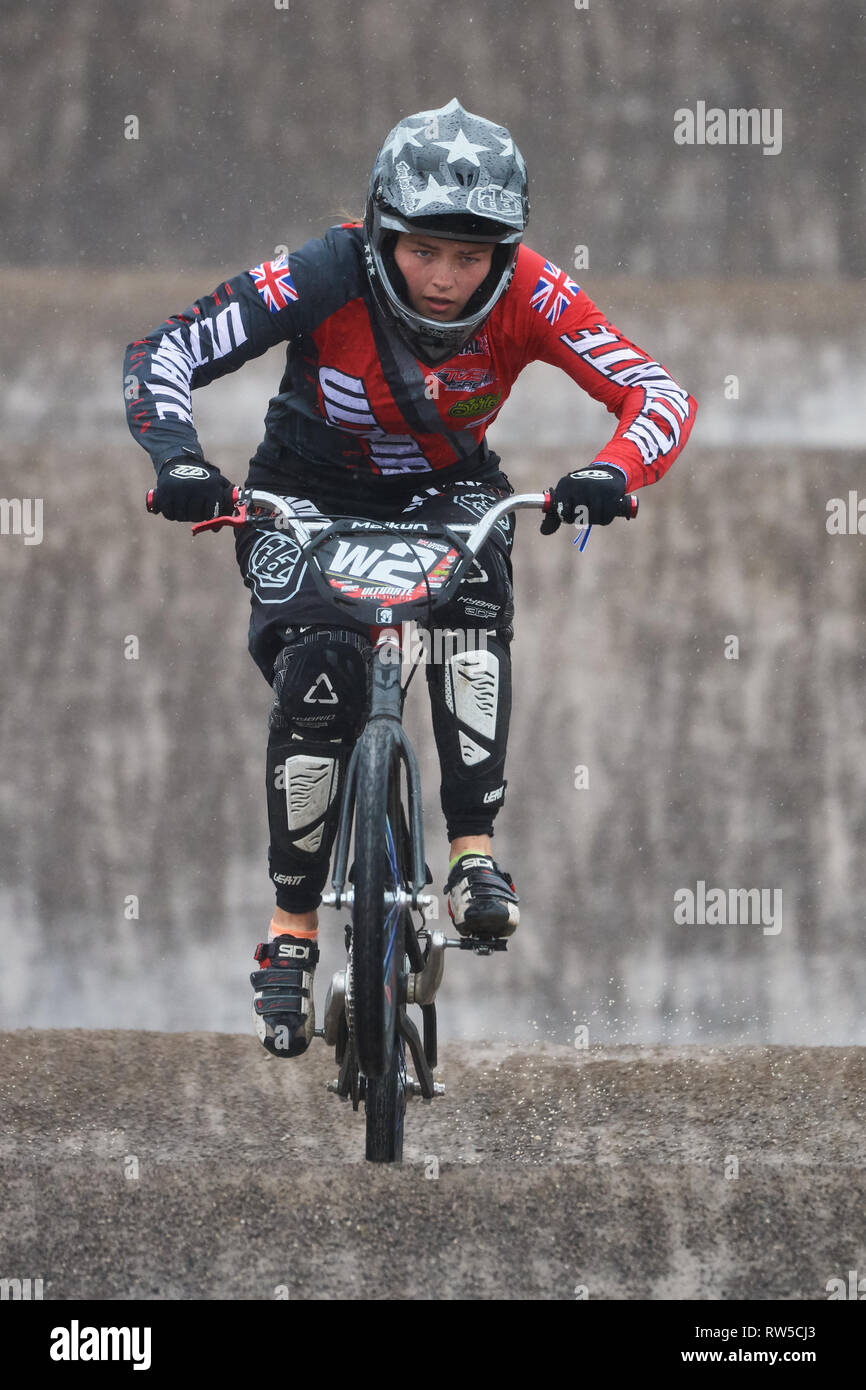BMX track racing. Rider in women's sprint race event. In difficult conditions from stormy cross winds and heavy rain. Stock Photo