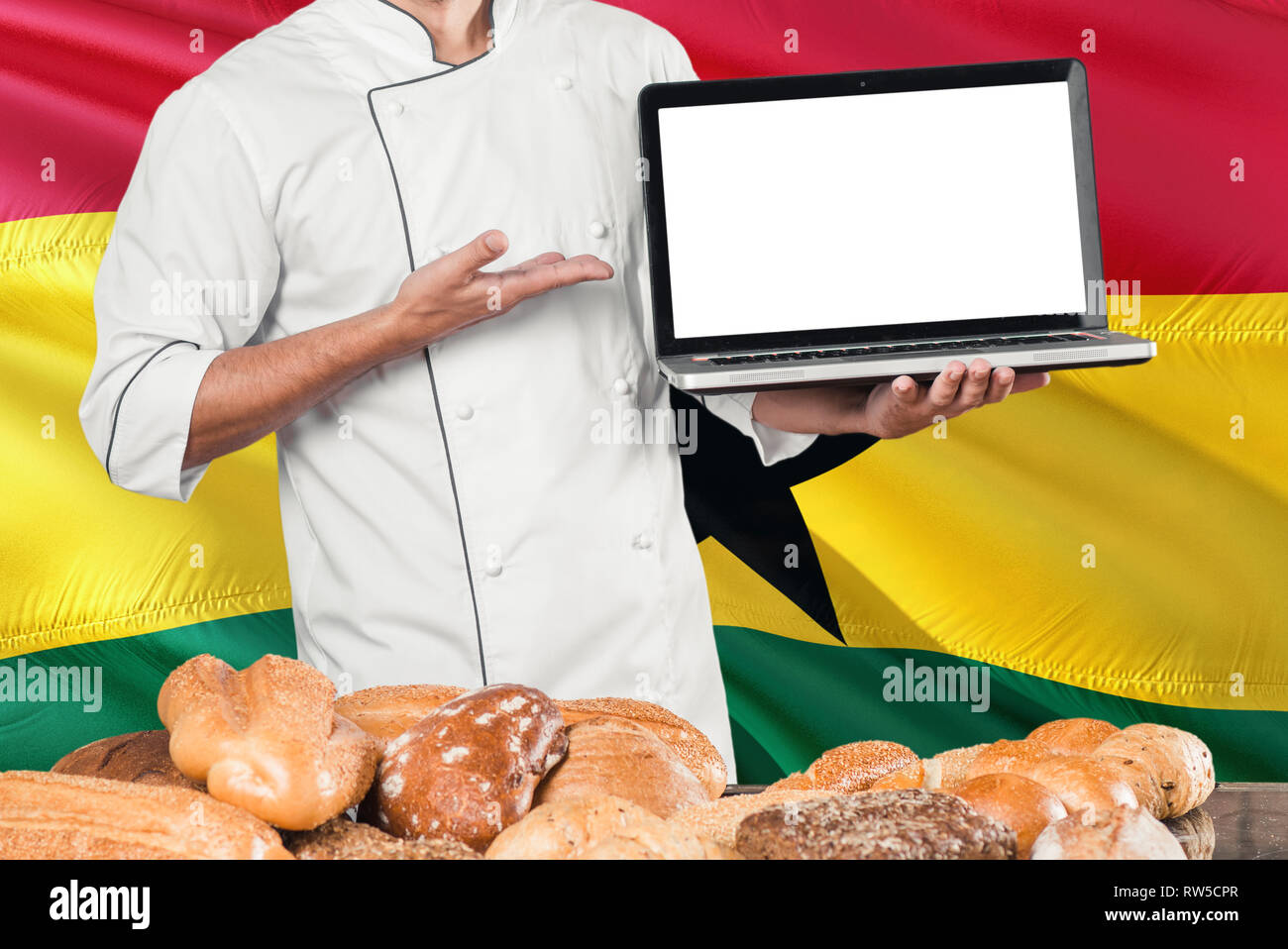 Ghanaian Baker holding laptop on Ghana flag and breads background. Chef