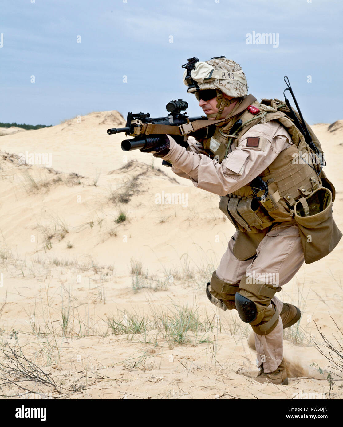 U.S. soldier runs through the desert shooting a gun with grenade launcher Stock Photo Alamy