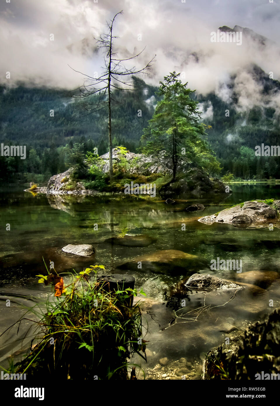 mystic mountain lake Hintersee with rock in green water at rainy day Stock Photo