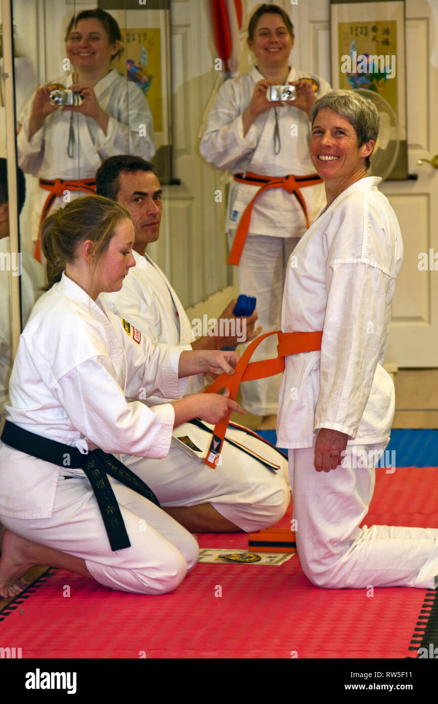 middle age woman, receives orange belt; karate class; accomplishment;  instructors; skill; martial art; self defense, vertical; MR Stock Photo -  Alamy