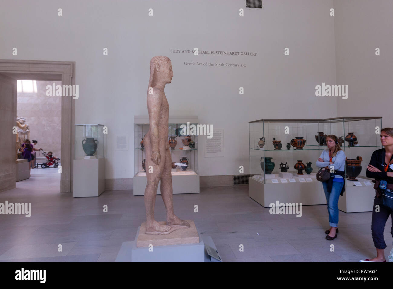 Two women observing the Marble statue of a kouros (youth), Egyptian art