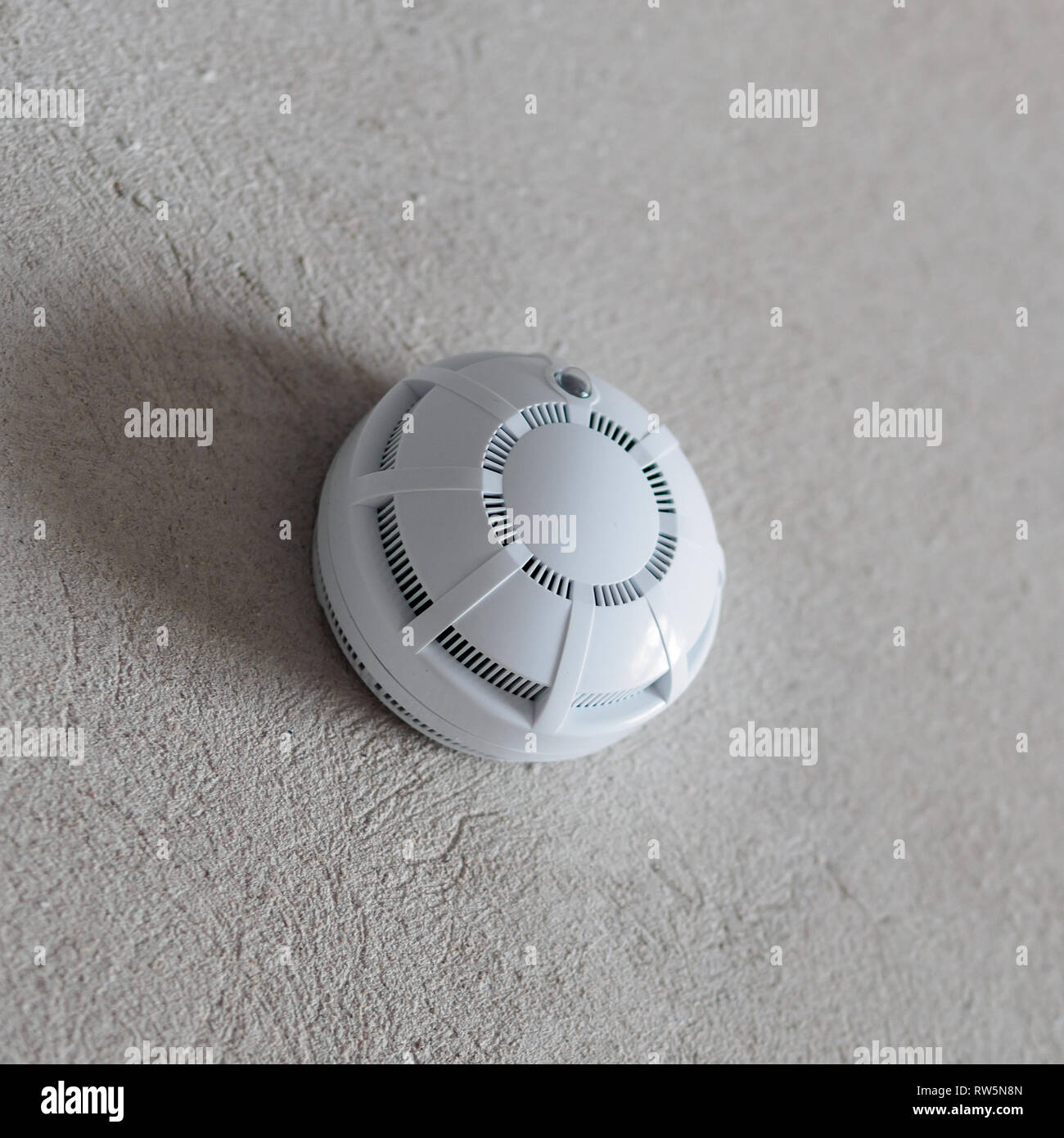 Smoke detector fire alarm on the grey wall. Copyspace for text. Stock Photo