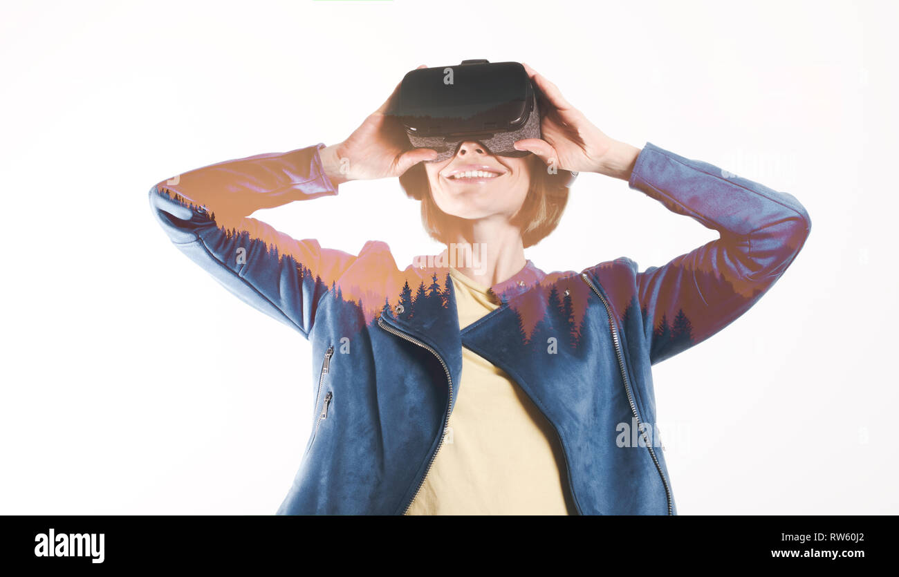 A young woman is wearing virtual reality glasses and reaching for