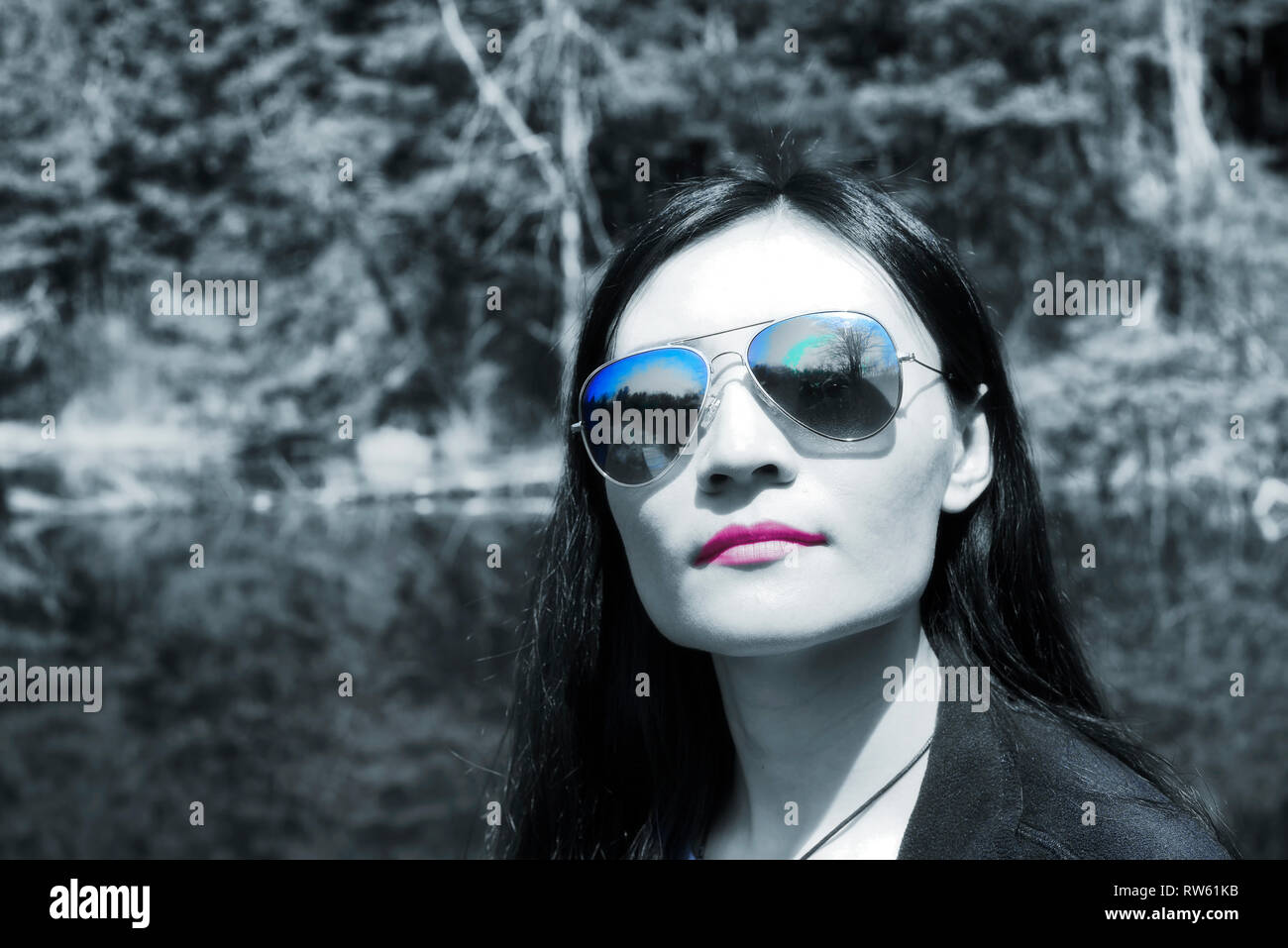 A chinese woman wearing blue sunglasses at Topsmead state forest in Litchfield Connecticut on a spring day abstract black and white with blue accents  Stock Photo