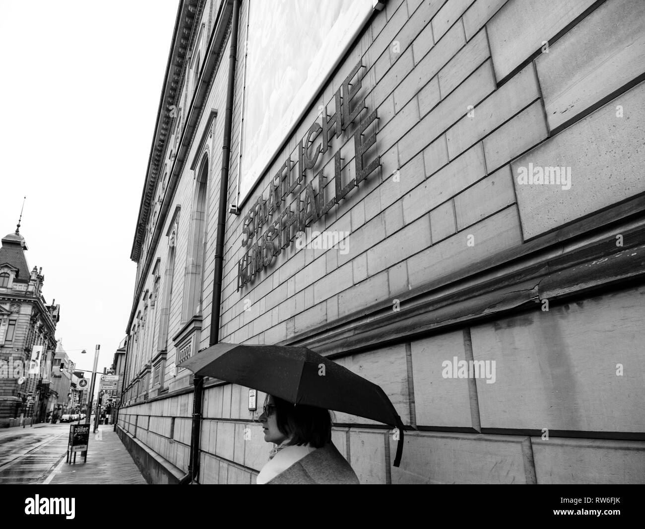 Karlsruhe, Germany - Oct 29, 2017: Staatliche Kunsthalle Karlsruhe State Art Gallery on Hans-Thoma-Strasse street with woman with umbrella on rainy day - black and white Stock Photo