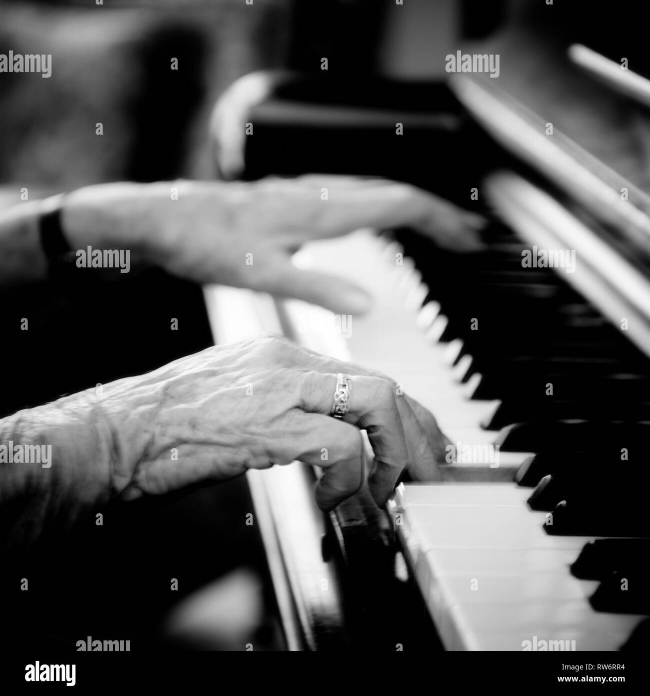 Ninety-two year old Jean McDougall plays the piano in her home. Her beautiful textured hands fly across the keys of the piano. Stock Photo