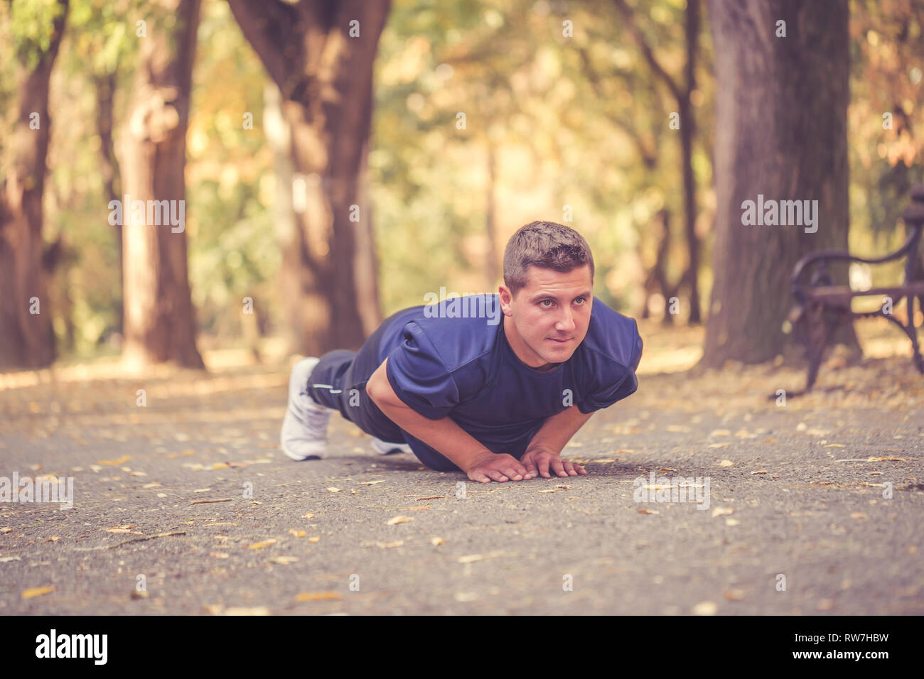 Picture of a young athletic man doing push ups in the park, preparing ...