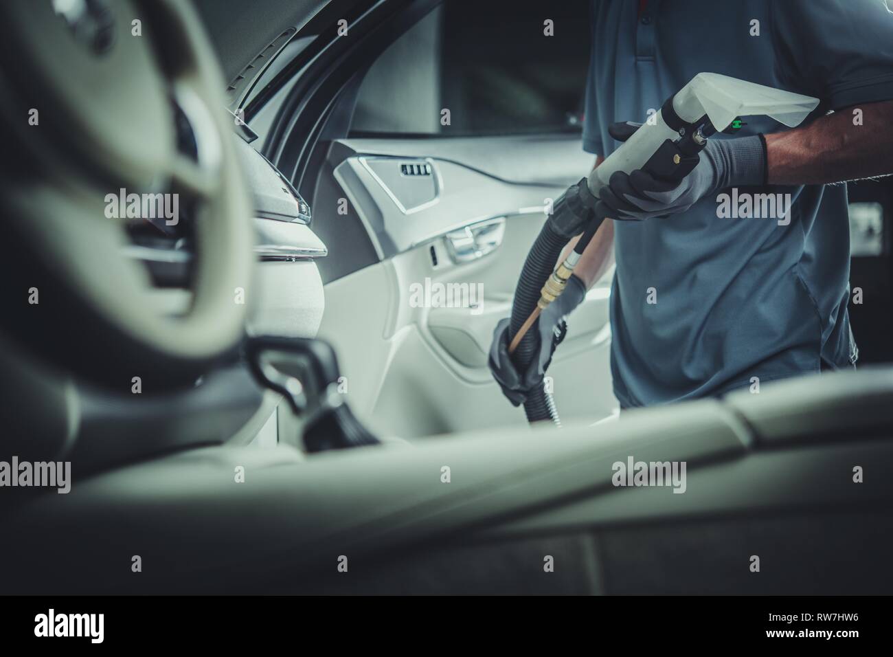 Professional Car Vacuuming Service. Worker with Commercial Grade Vacuum