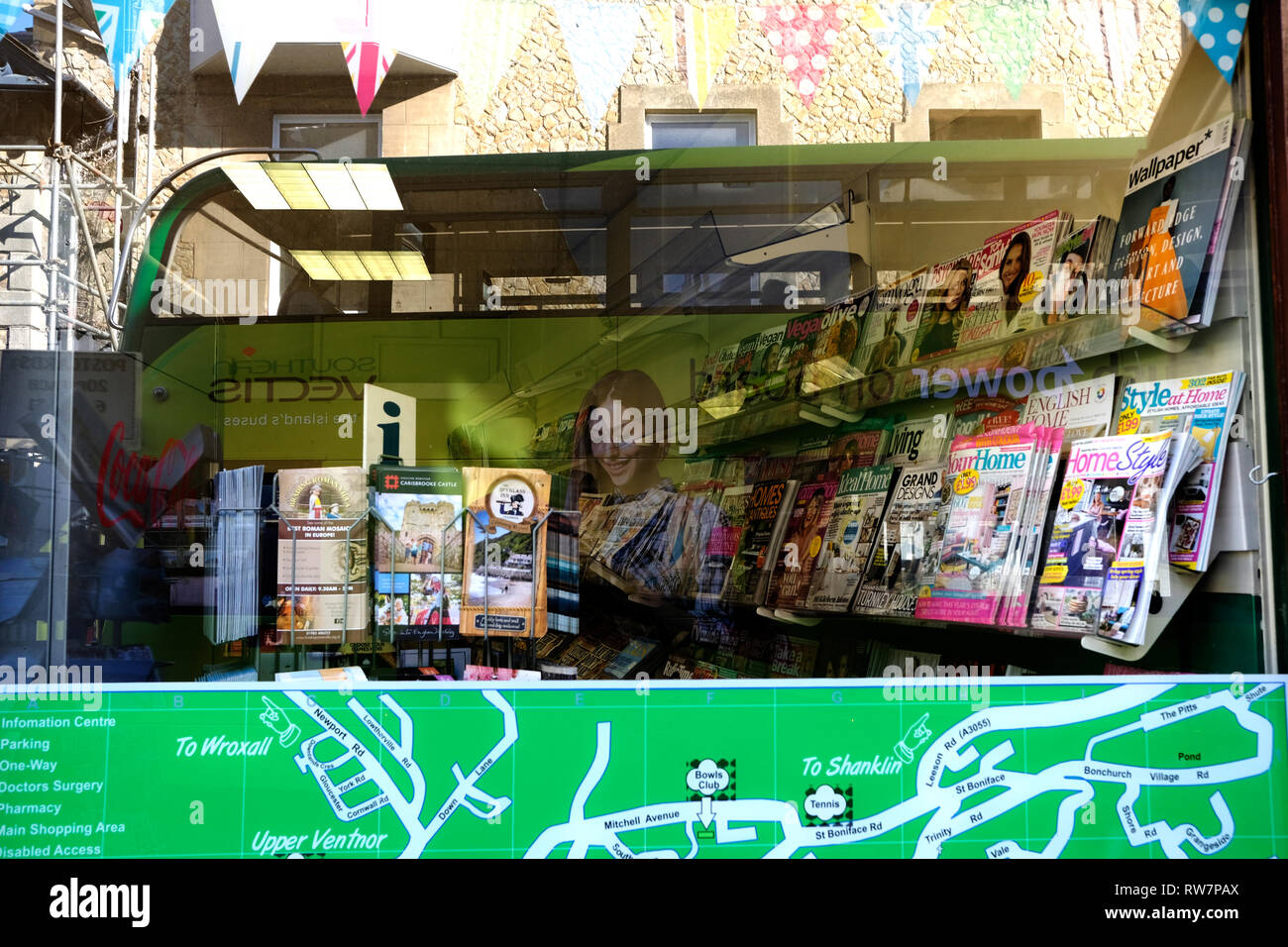 Reflections in a shop window, showing a Southern Vectis double decker bus and the magazine rack of a local newsagents in Ventnor, Isle of Wight, UK. Stock Photo