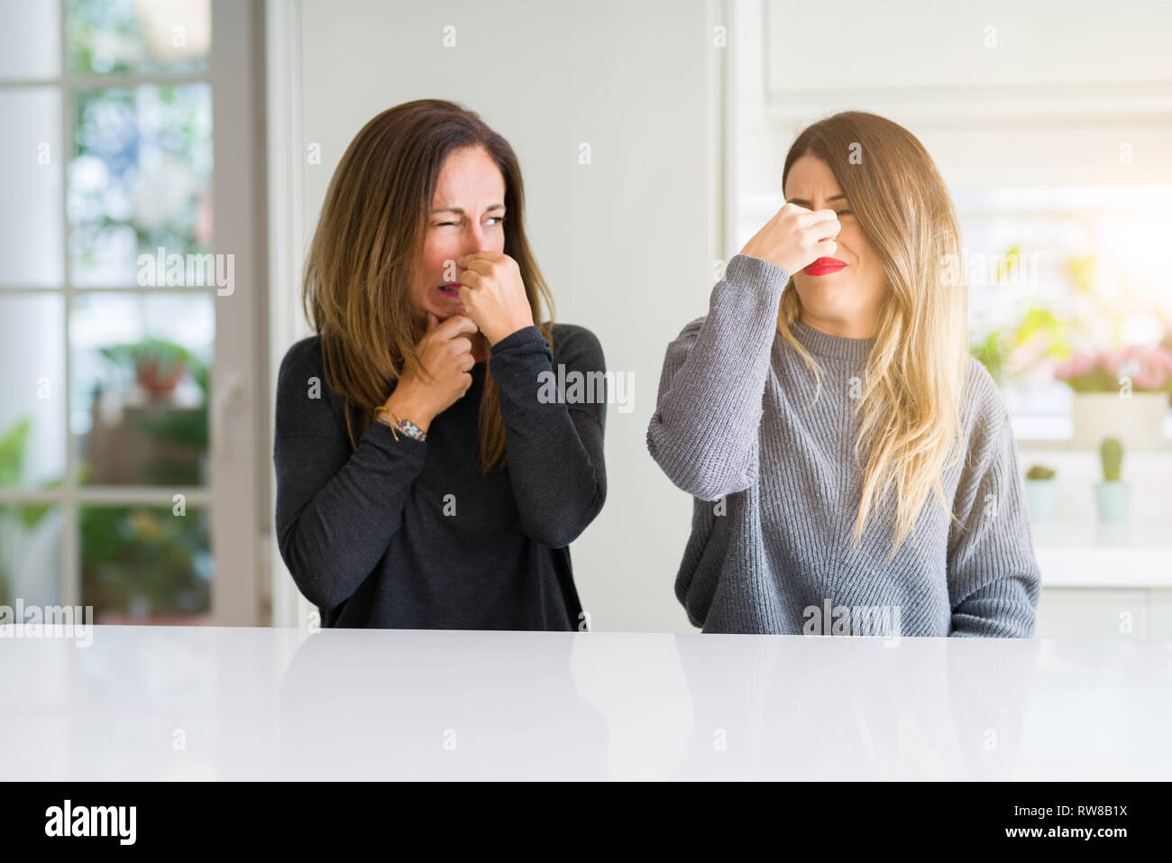 Beautiful family of mother and daughter together at home smelling