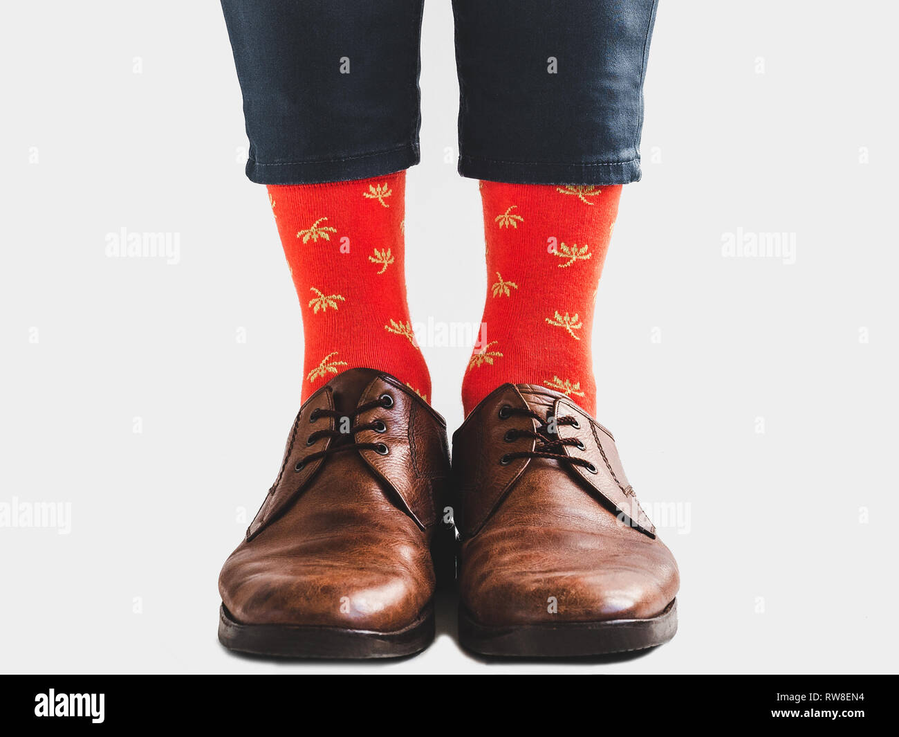 Men's legs, trendy shoes, blue pants and bright socks on a white