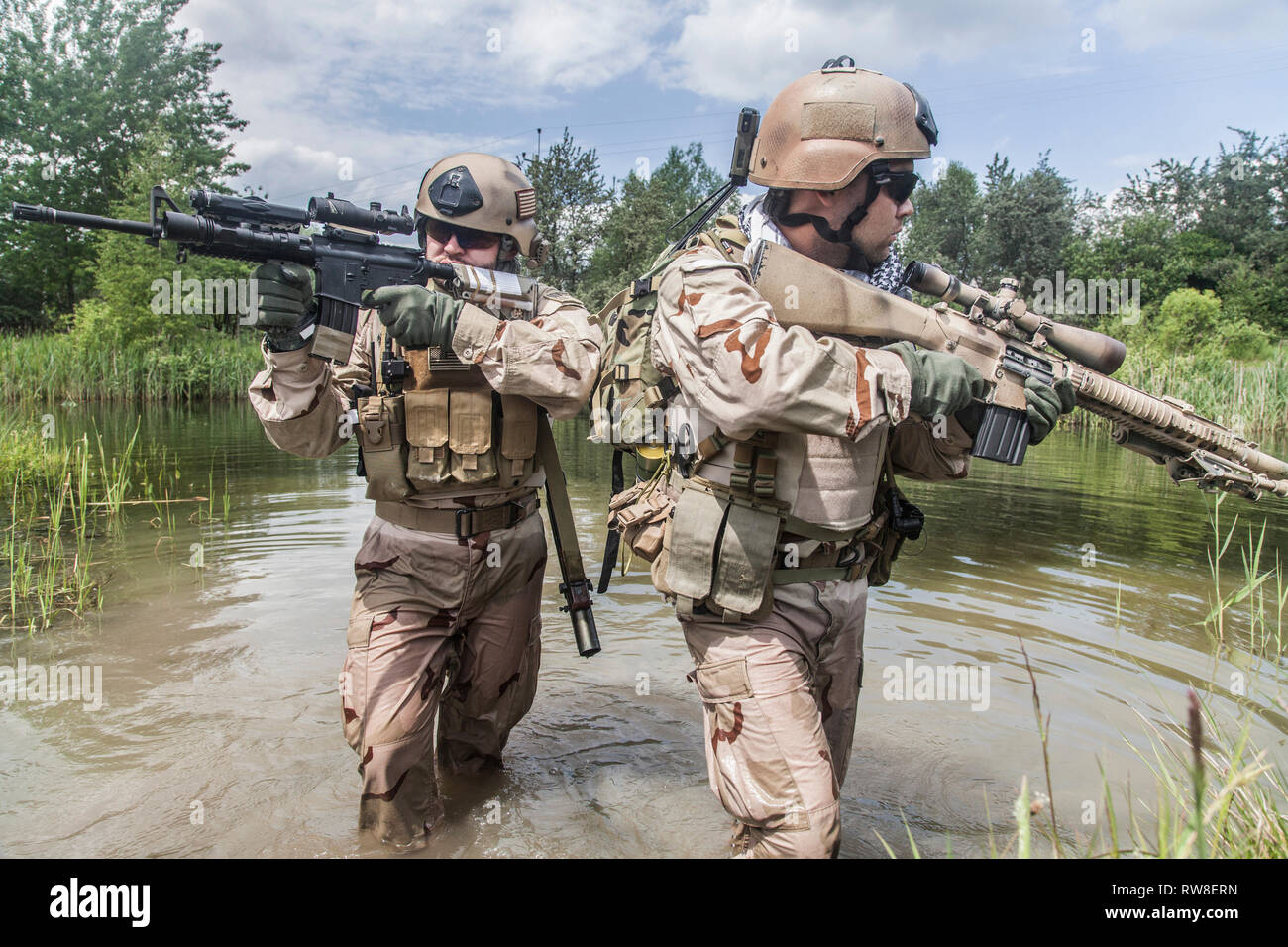 Navy SEALs crossing the river with weapons. Stock Photo