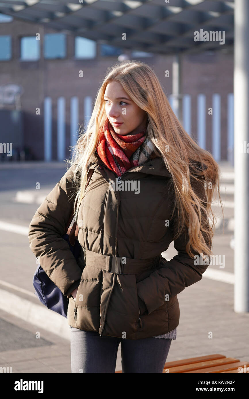 candid street style image of young woman waiting at bus station Stock Photo