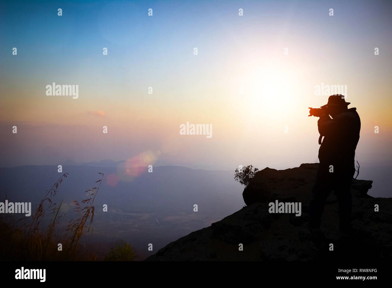 Vintage style of abstract blurred as orange light autumn. The young photographer on mountains and trees, looking at the scenery during golden sunrise  Stock Photo