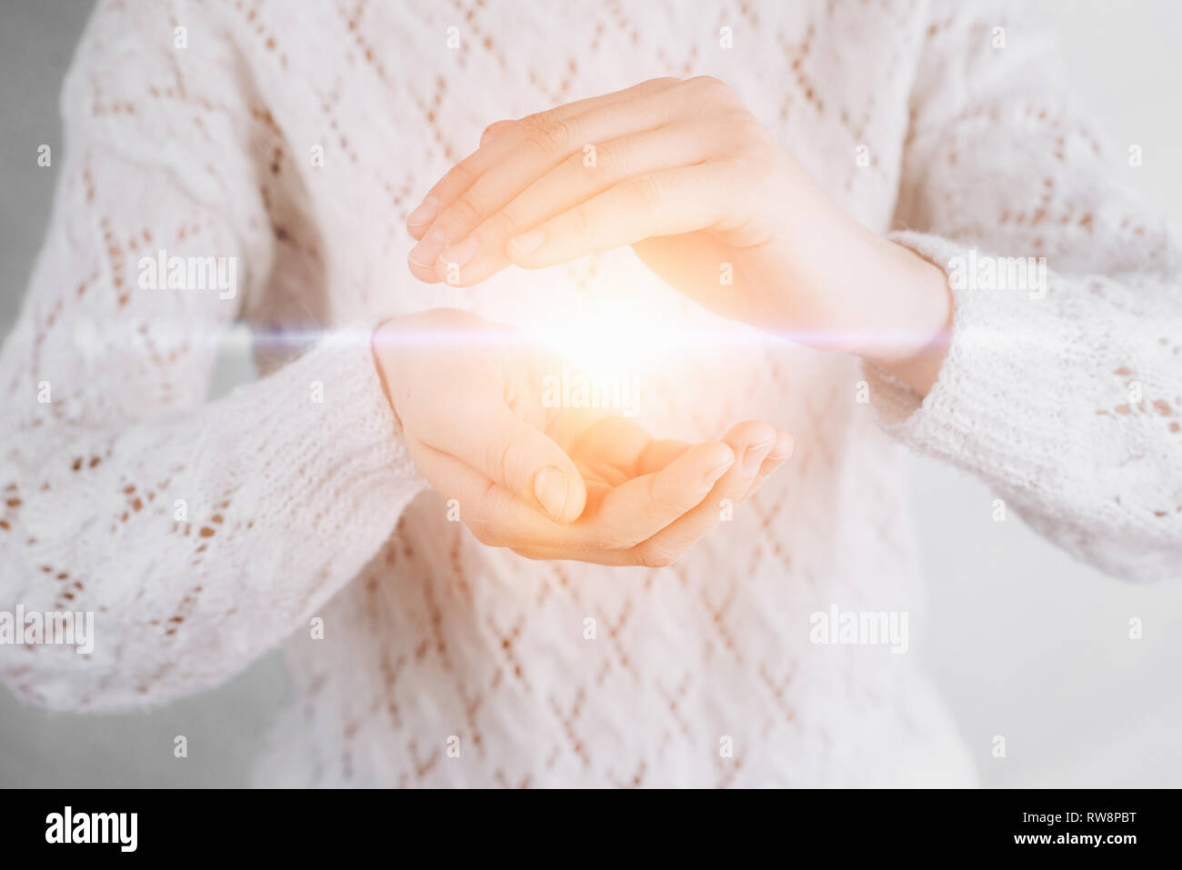 Light in young woman hands offering help, protection and support symbol. Sharing hope concept Stock Photo