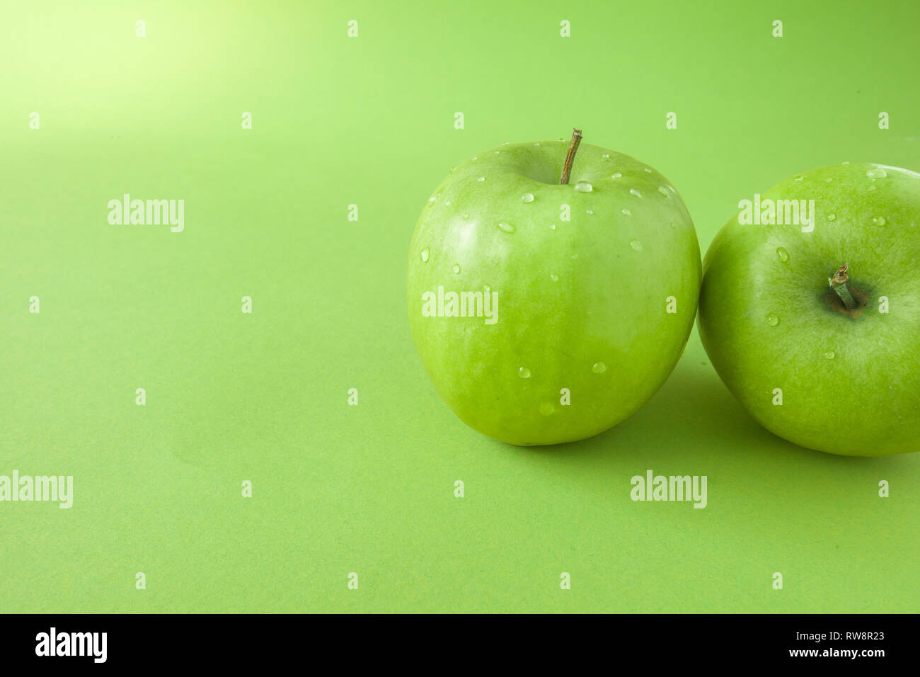 Perfect Fresh Green Apple Isolated on green Background with water drop in Full Depth of Field Stock Photo