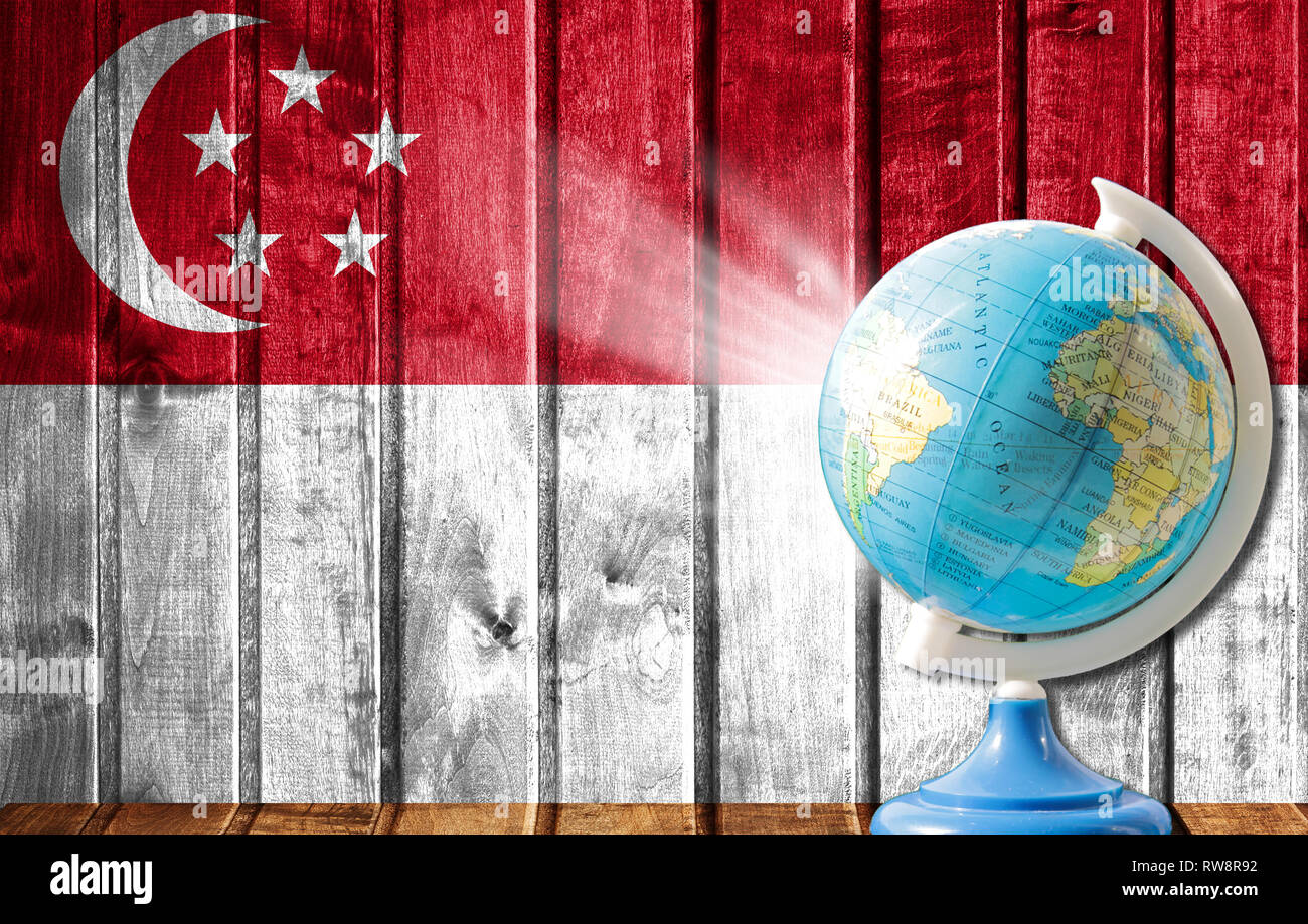 Globe with a world map on a wooden background with the image of the flag of Singapore. The concept of travel and leisure abroad. Stock Photo