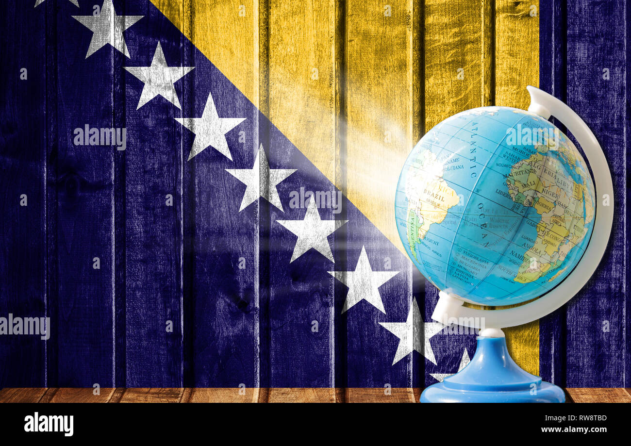 Globe with a world map on a wooden background with the image of the flag of Bosnia and Herzegovina. The concept of travel and leisure abroad. Stock Photo
