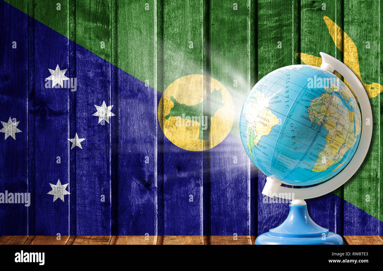 Globe with a world map on a wooden background with the image of the flag of Christmas Island. The concept of travel and leisure abroad. Stock Photo