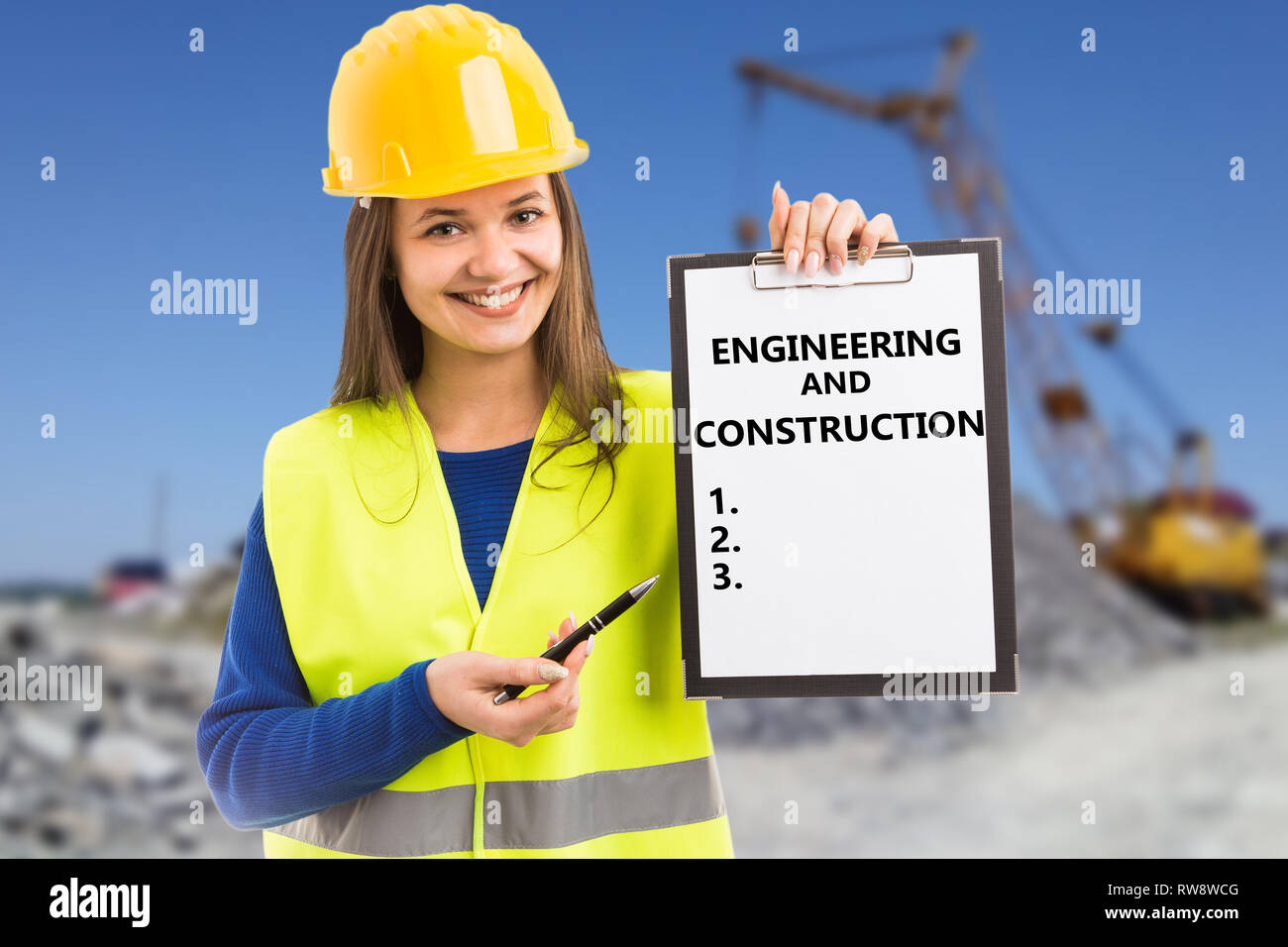 Builder woman wearing work attire and safety hardhat showing clipboard with numbered list having engineering and construction title Stock Photo