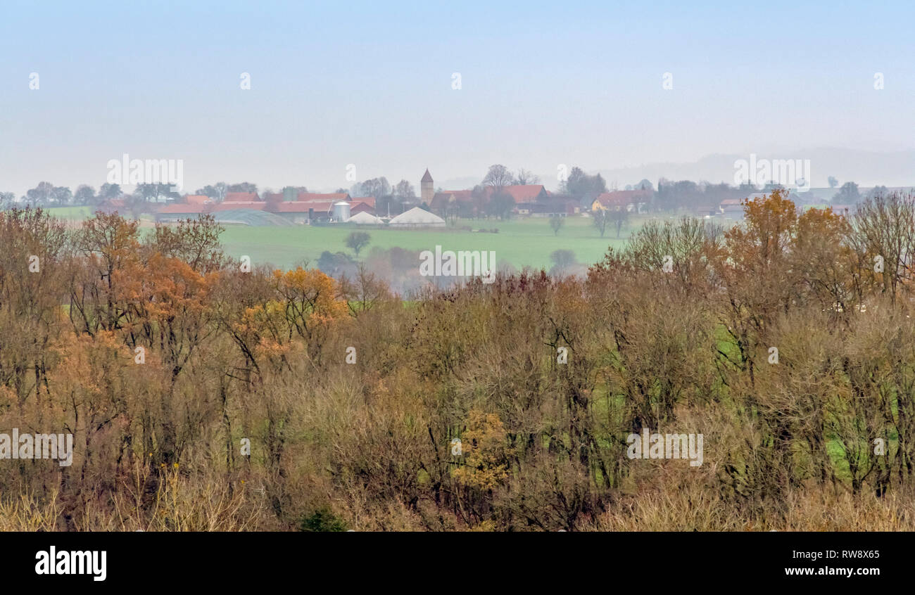 distant rural village behind autumn forest scenery Stock Photo