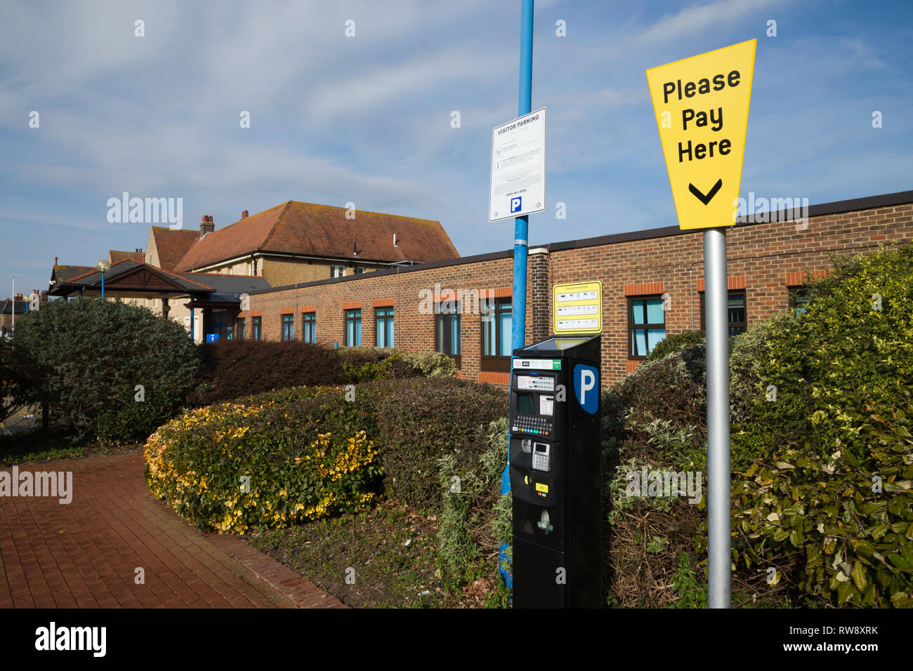 Pay and display ticket machine / pay point with Please Pay Here sign