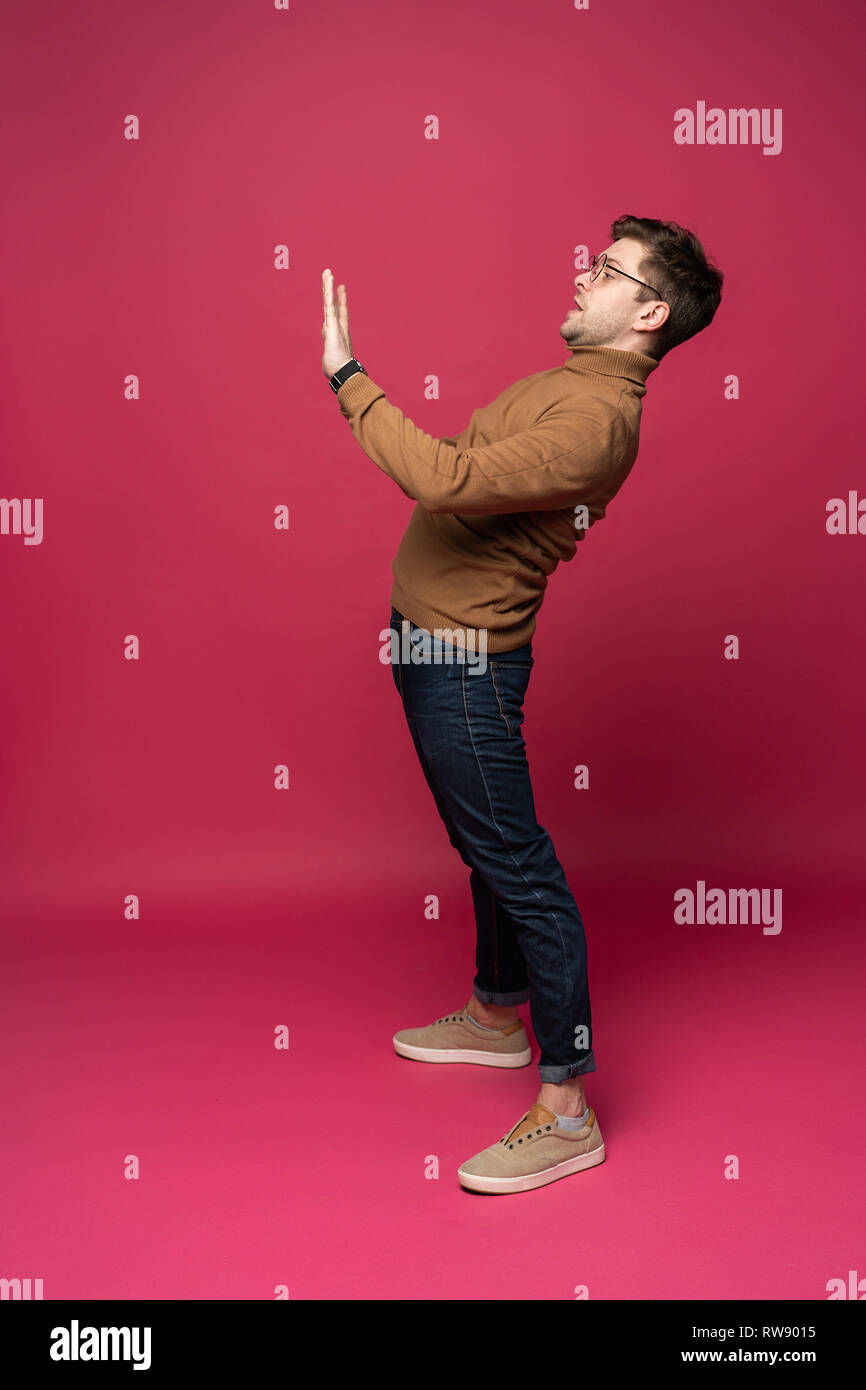 full body picture of a young casual man presenting something on pink ...