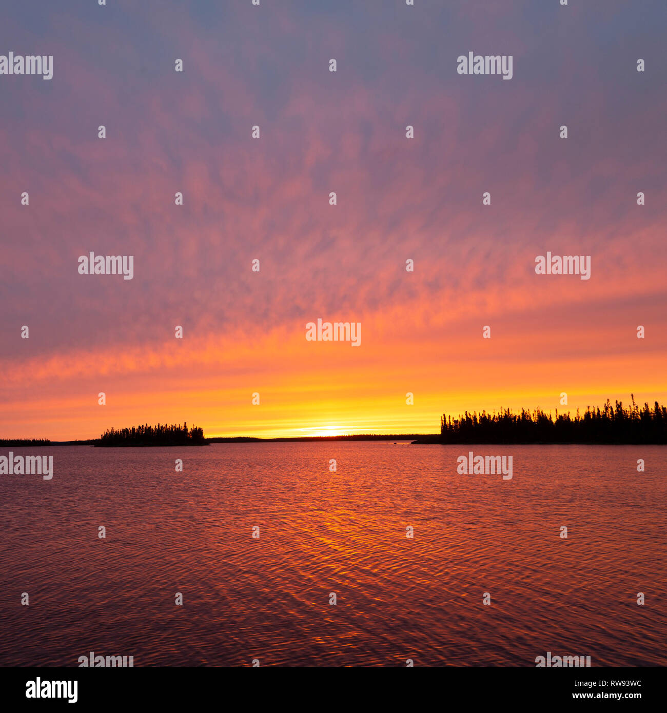 Golden morning at Egenolf Lake in Manitoba, Canada. The sun peeks above the horizon. Stock Photo