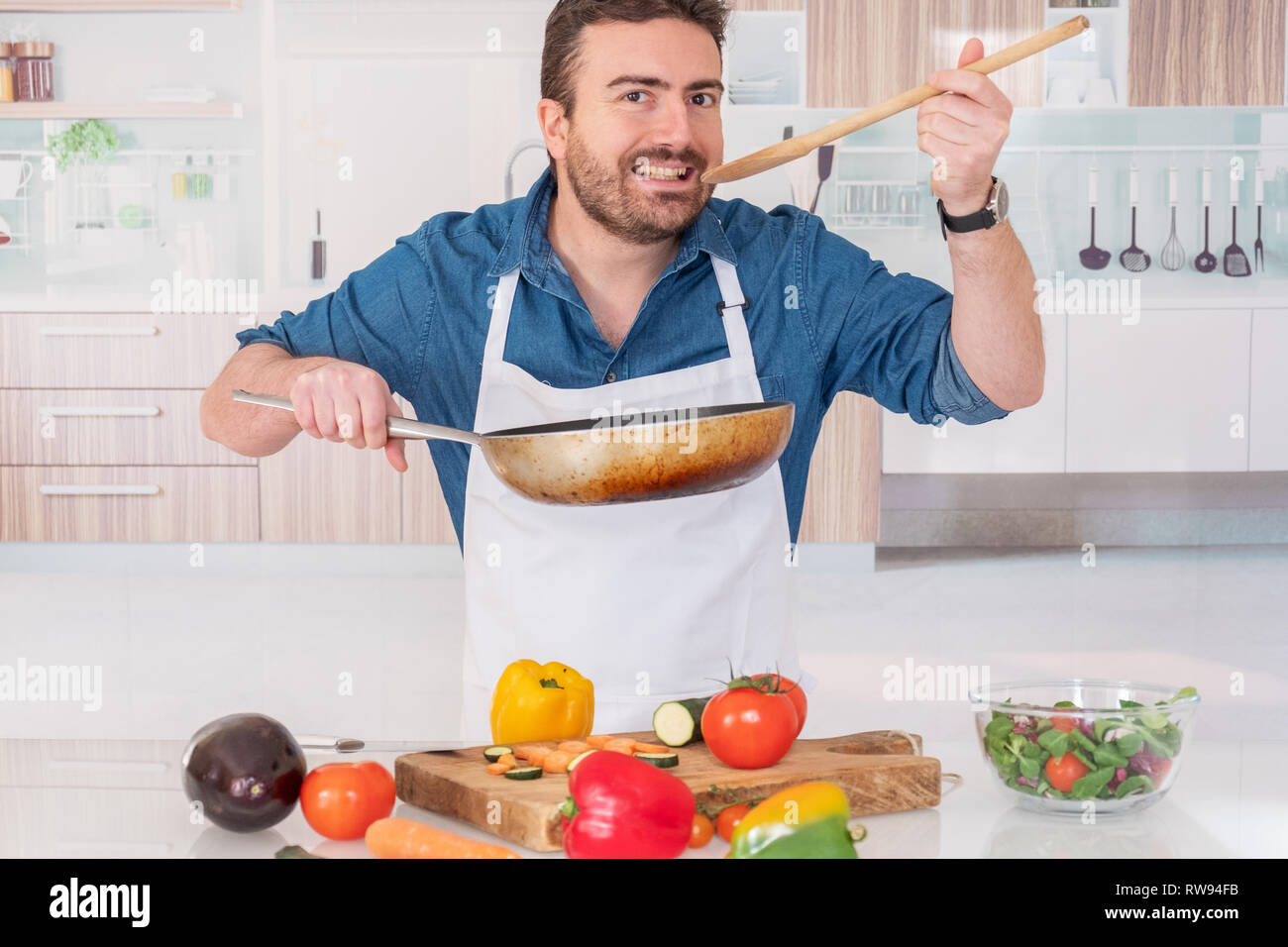 https://c8.alamy.com/comp/RW94FB/cheerful-young-man-tasting-food-while-cooking-at-home-RW94FB.jpg