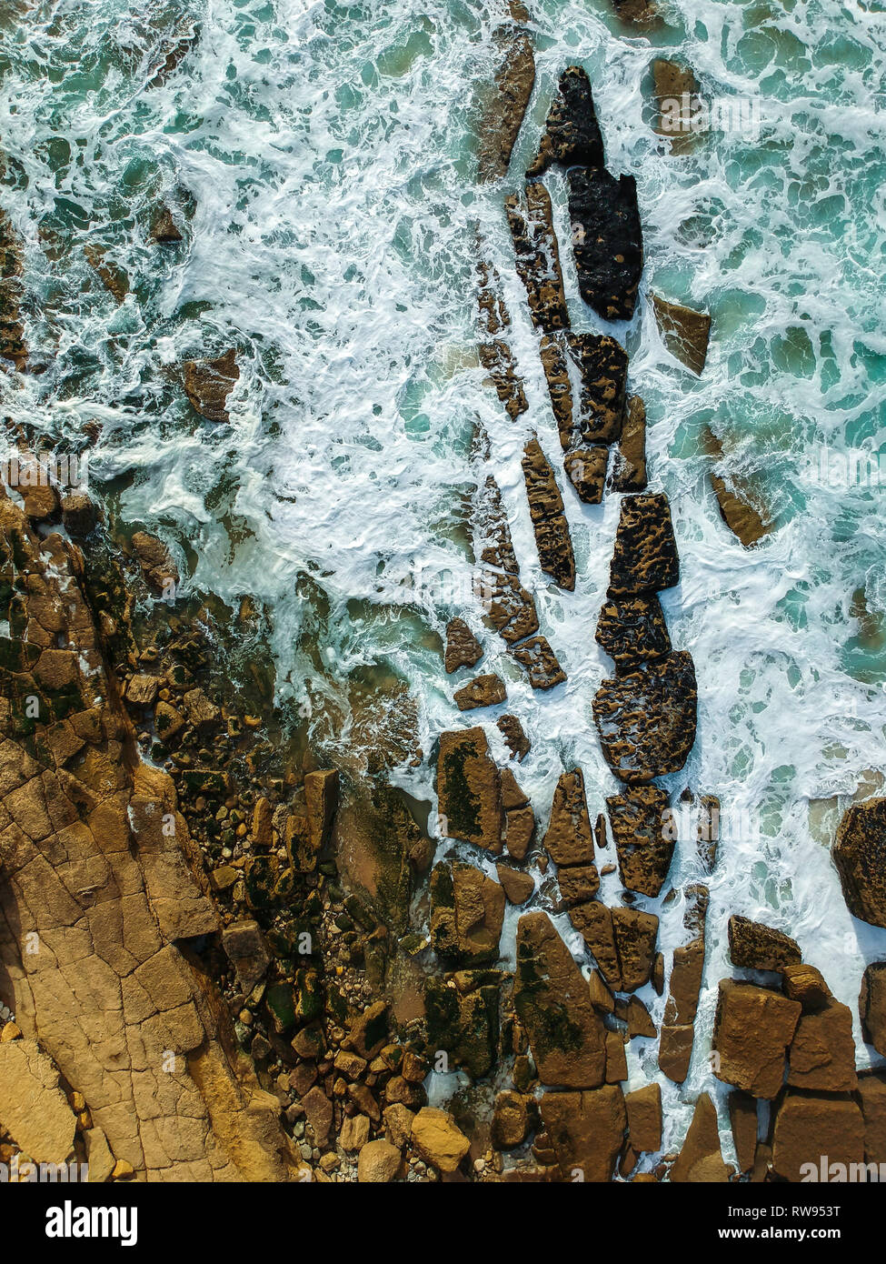 Top view of a beautiful sandy beach aerial shot with the waves rolling into the shore, some rocks present Stock Photo