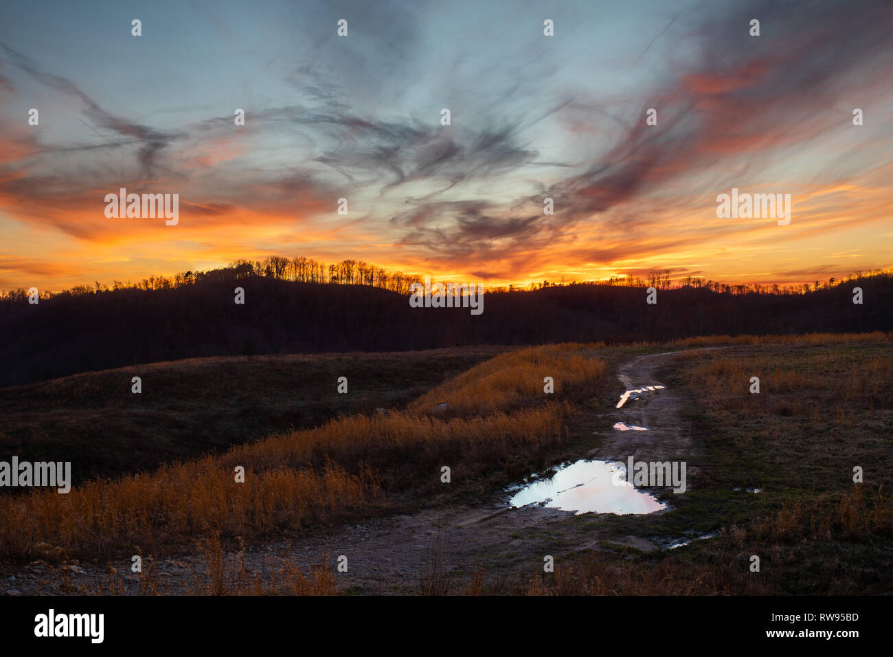 The sinking sun lights up the sky with color in this rural scene in