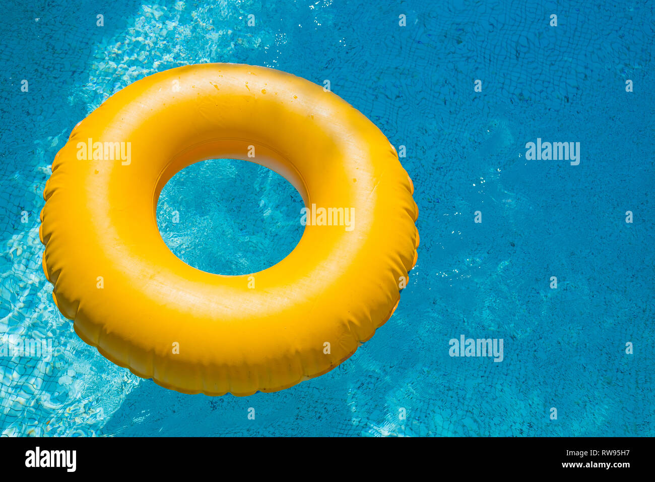 floating ring on blue water swimpool with waves reflecting in the ...