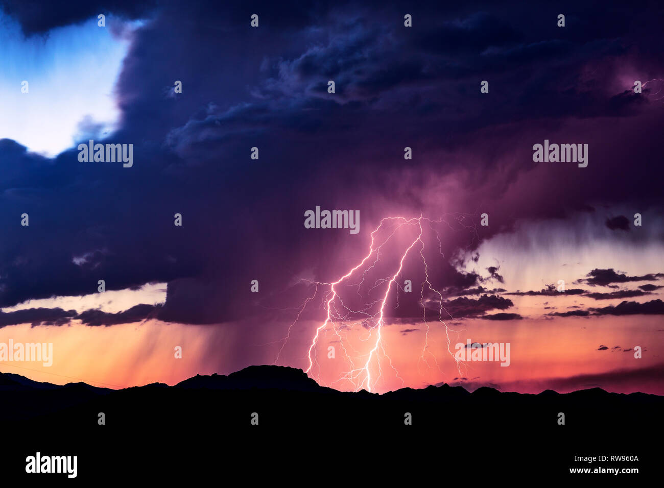 Scenic desert landscape with a lightning bolt striking in a thunderstorm cloud at sunset near