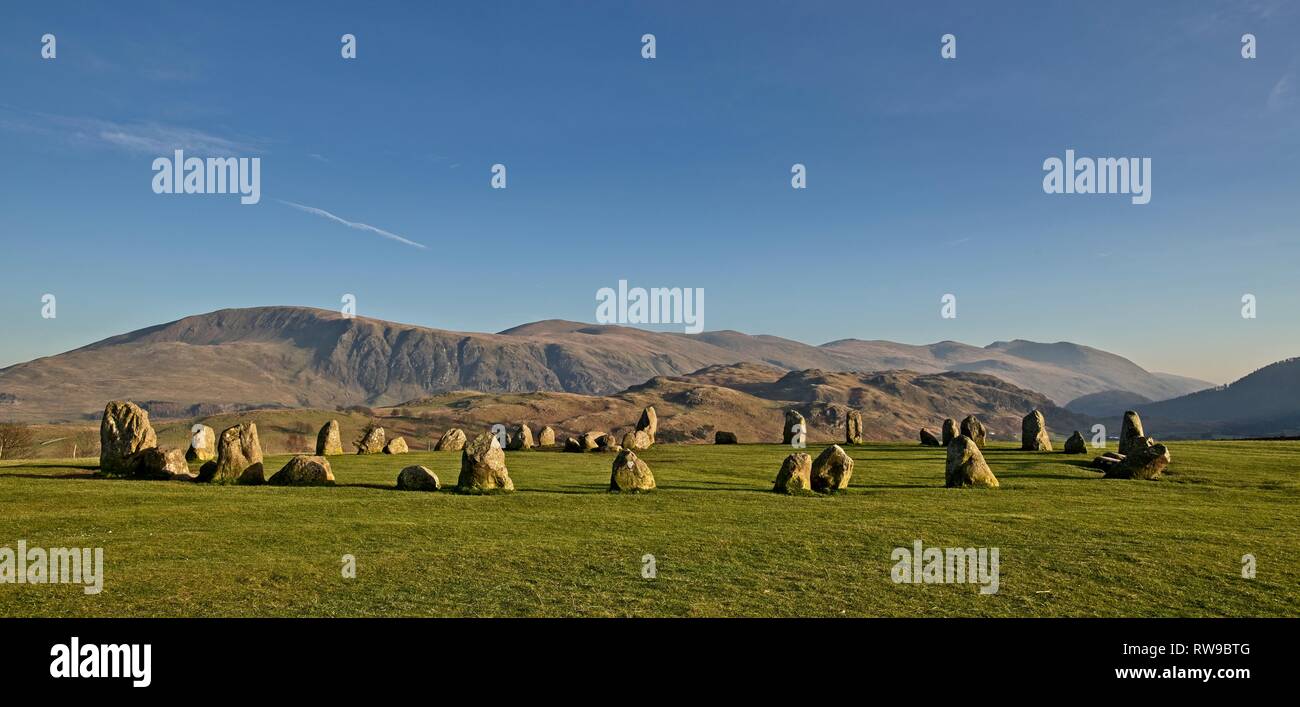 Castlerigg stone circle illuminated by low winter sun with Clough Head and the Helvellyn ridge behind Stock Photo