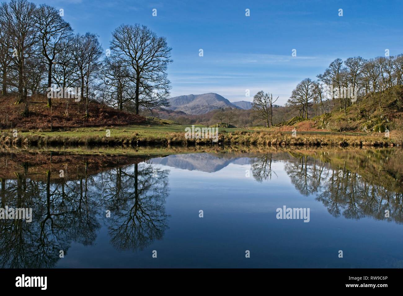 Mirror-like reflections of Wetherlam and the Coniston fells on the River Brathay near Elterwater Stock Photo