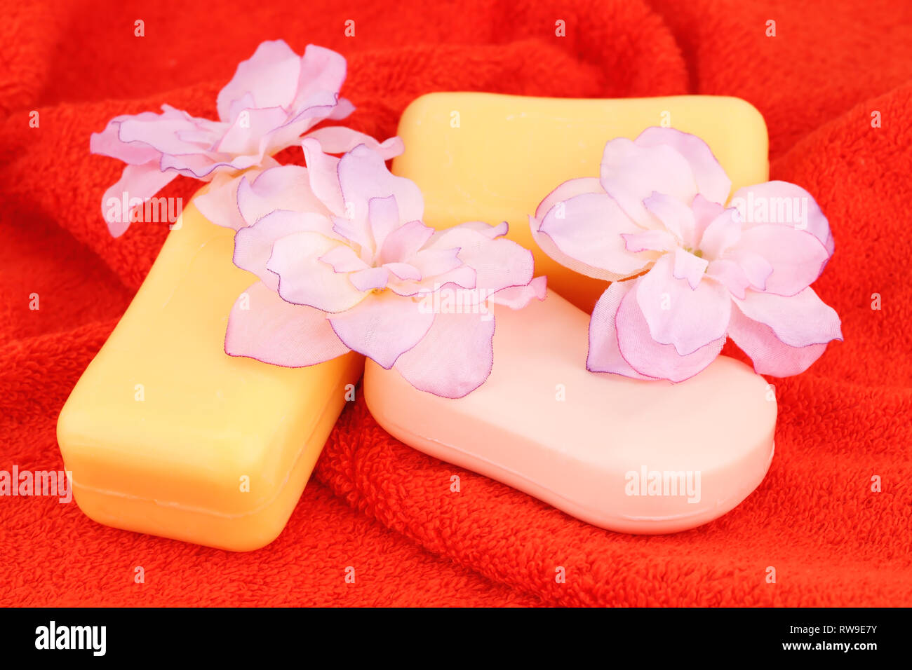 Colorful soaps and flowers on red towel. Stock Photo