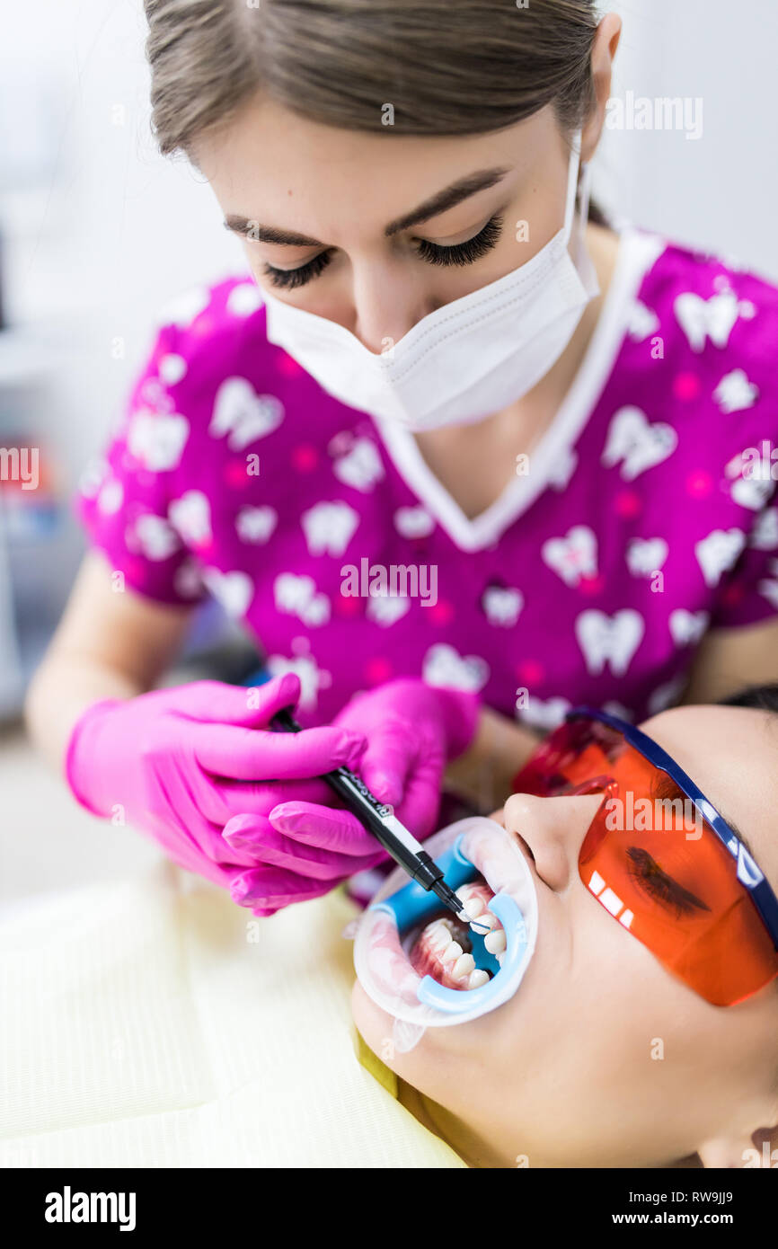 Professional female dentist wearing mask and gloves holding syringe