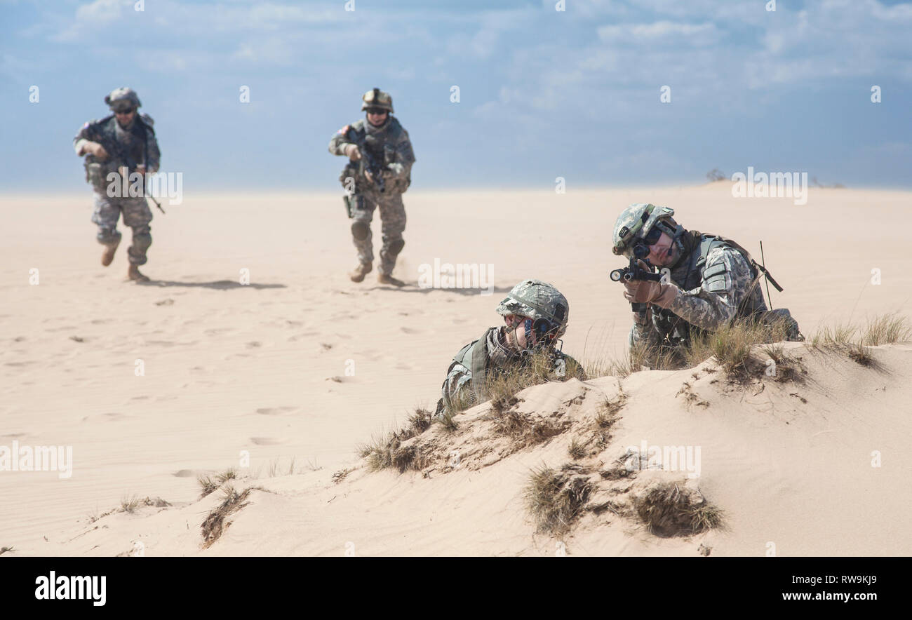 Team of United States airborne infantry men with weapons in action in desert. Stock Photo