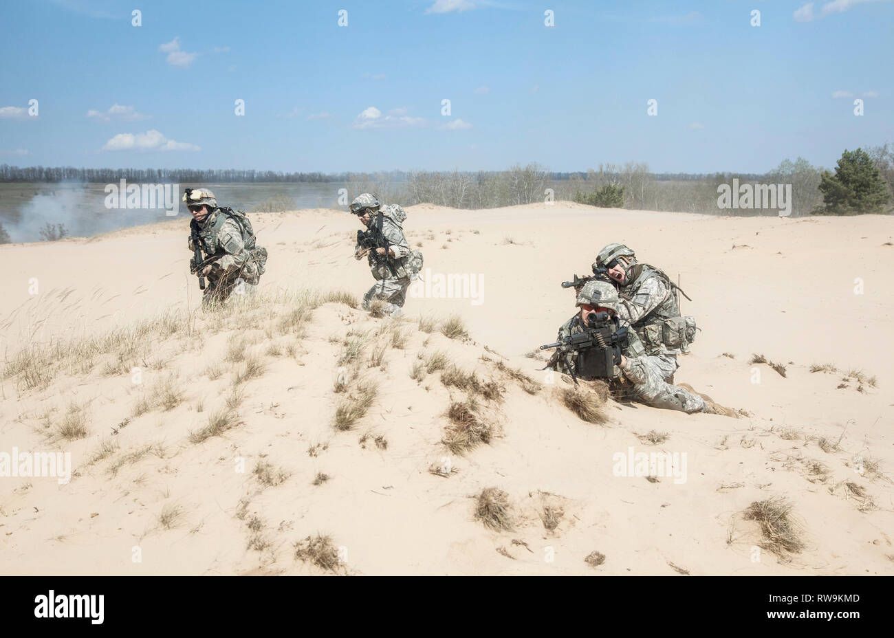 Team of United States airborne infantry men with weapons in action in desert. Stock Photo