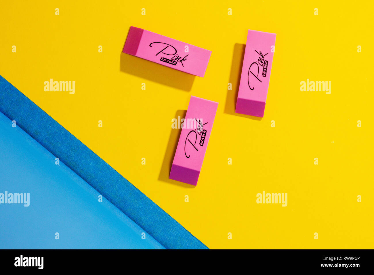 A graphically pleasing photo of pink erasers on a colorful yellow background with a triangle of blue. Stock Photo