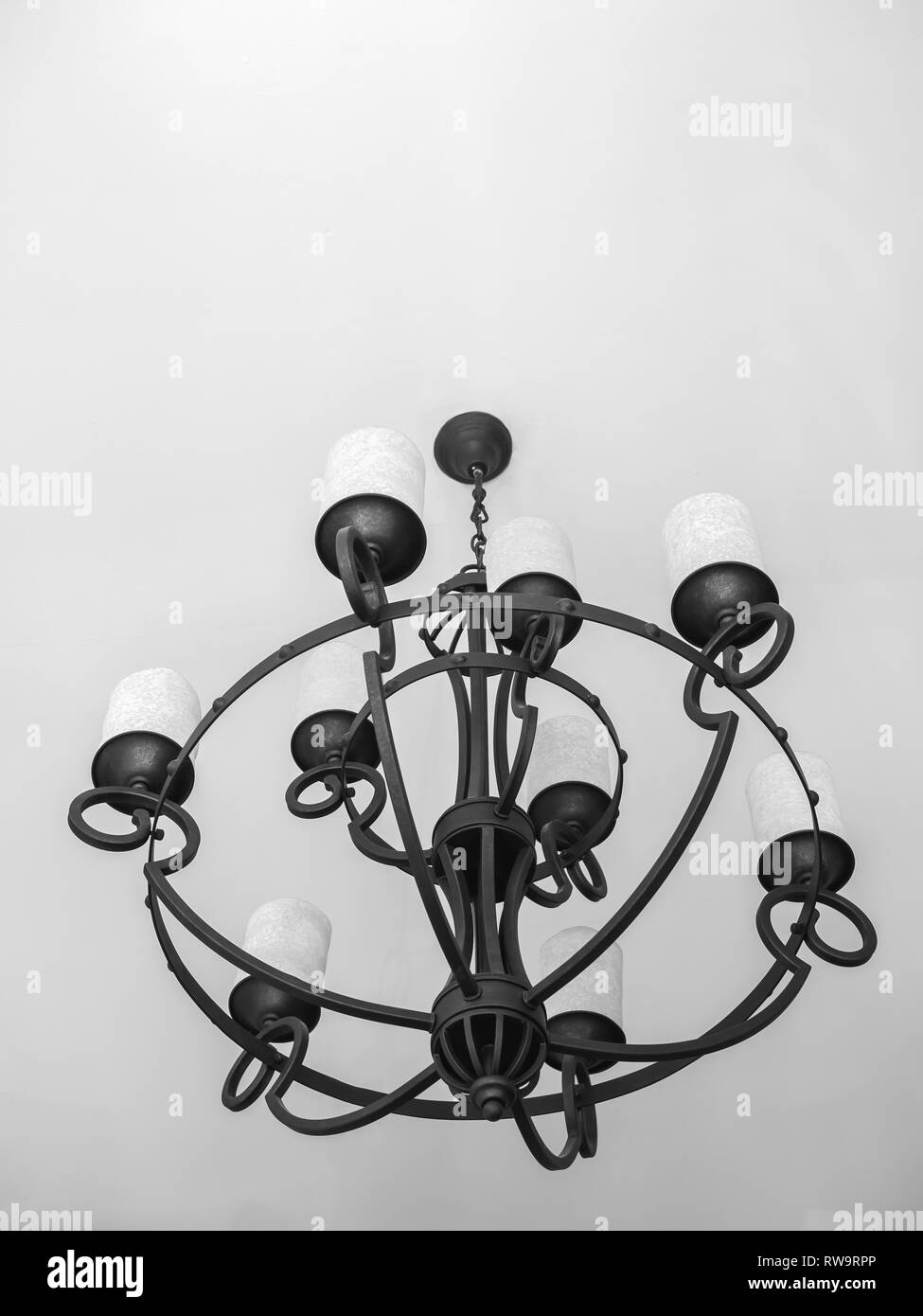 Vintage black chandelier with white candles on white ceiling background